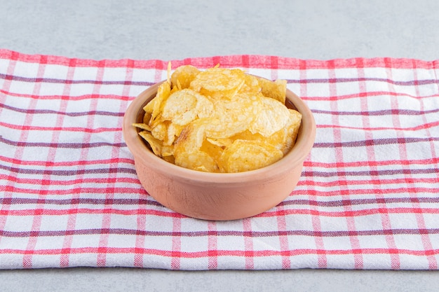 Cuenco de cerámica de deliciosas patatas fritas crujientes sobre fondo de piedra.