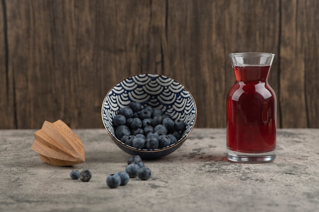 Cuenco de cerámica de deliciosos arándanos frescos y vaso de jugo