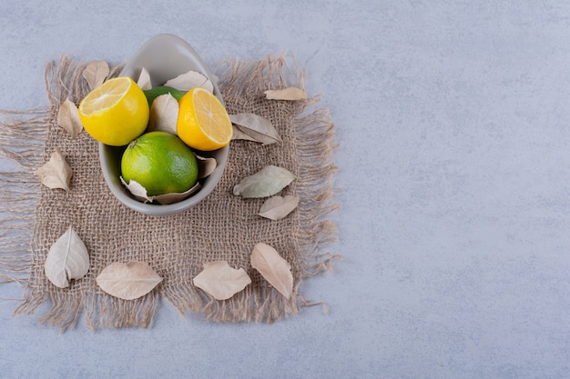 Cuenco de cerámica de jugosos limones frescos en la mesa de piedra.