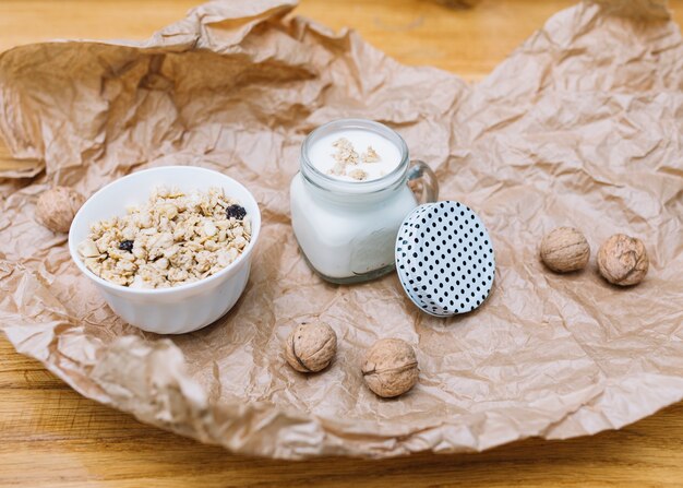 Cuenco de cereales; Leche y nueces sobre papel marrón desmenuzado.