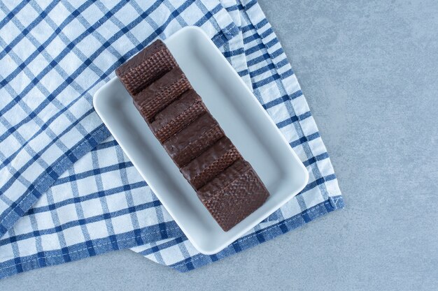 Un cuenco de chocolate recubierto de barra de barquillo crujiente sobre la toalla, sobre la mesa de mármol.