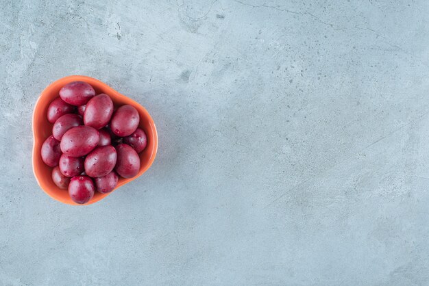 Un cuenco de ciruelas fermentadas, sobre la mesa de mármol.