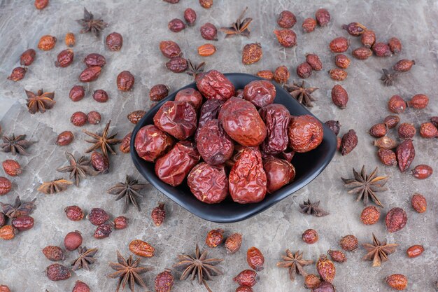 Cuenco de escaramujos secos sobre fondo de piedra.