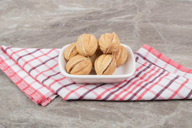 Cuenco de galletas con forma de nuez sobre mantel. Foto de alta calidad