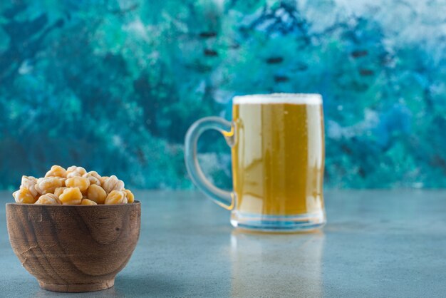 Un cuenco de garbanzos y un vaso de cerveza, sobre la mesa de mármol.