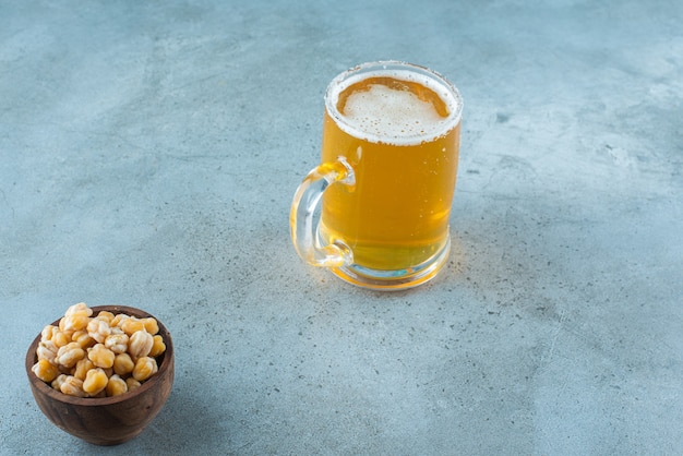 Un cuenco de garbanzos y un vaso de cerveza, sobre la mesa de mármol.