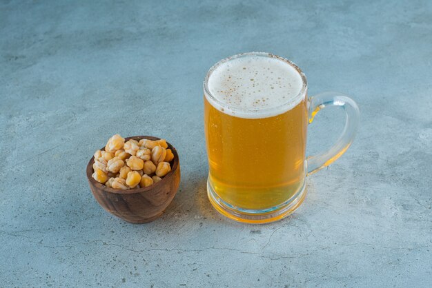 Un cuenco de garbanzos y un vaso de cerveza, sobre la mesa de mármol.