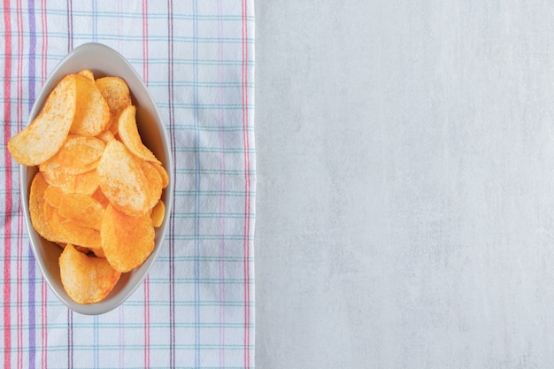 Cuenco gris lleno de patatas fritas picantes en piedra.