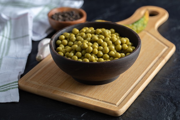 Cuenco de guisantes enlatados sobre tabla de madera.