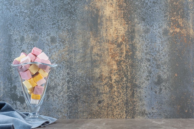 Foto gratuita cuenco de helado de cristal lleno con caramelos de colores sobre fondo gris.