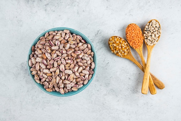 Un cuenco lleno de frijoles y tres cucharadas de madera de frijoles crudos.