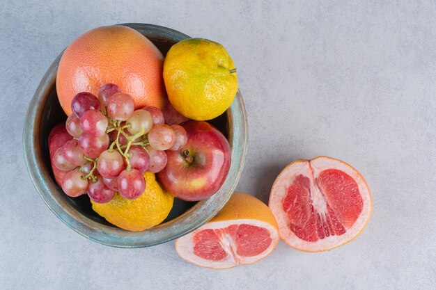 Cuenco lleno de fruta de temporada y pomelo medio cortado.