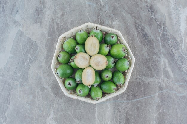 Cuenco lleno de jugosa feijoa en mármol.