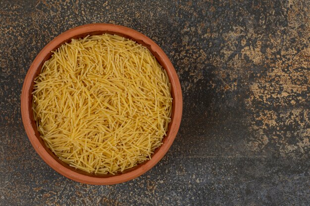 Cuenco de macarrones crudos sobre superficie de mármol.