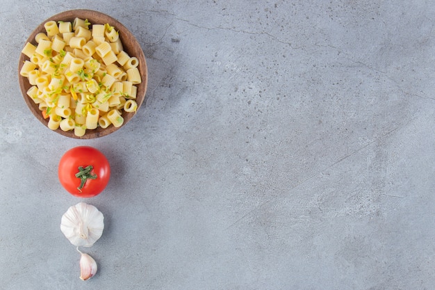 Cuenco de madera de deliciosa pasta hervida sobre fondo de piedra.