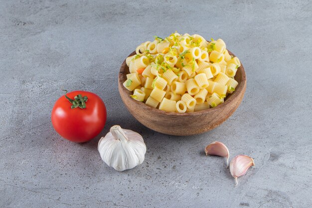 Cuenco de madera de deliciosa pasta hervida sobre la superficie de piedra.