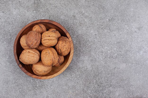 Un cuenco de madera lleno de nueces saludables en cáscaras duras