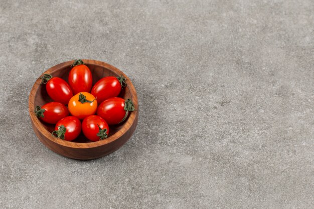 Cuenco de madera lleno de tomates cherry rojos.