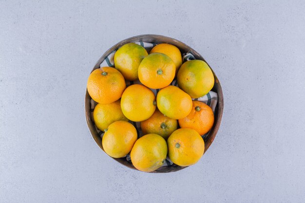 Cuenco de madera de mandarinas sobre fondo de mármol.