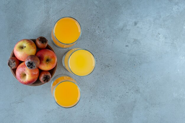 Un cuenco de madera de manzanas con vasos de jugo de naranja.