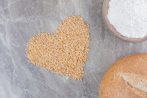 Foto gratuita un cuenco de madera con pan y granos de avena en la superficie de mármol