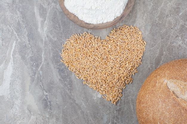 Un cuenco de madera con pan y granos de avena en la superficie de mármol