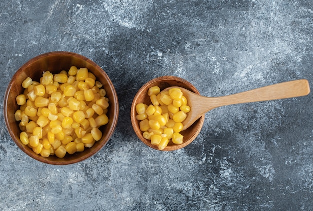 Un cuenco de madera de semillas de palomitas de maíz en mármol.