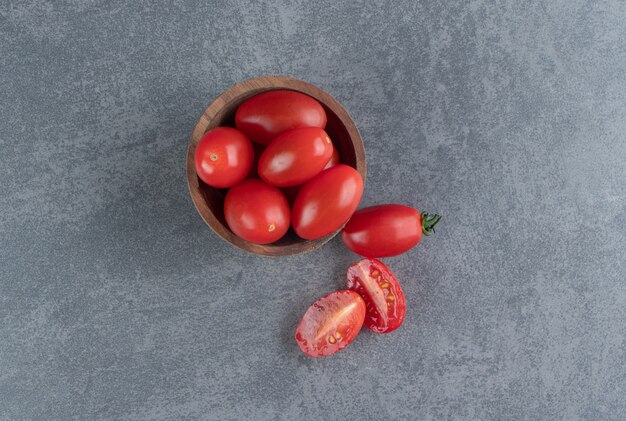 Un cuenco de madera de tomates cherry rojos.