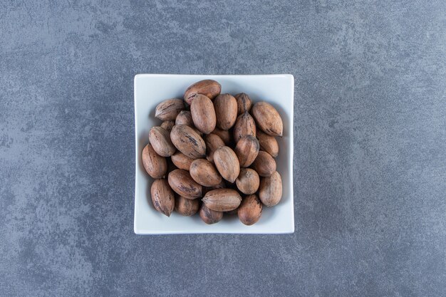 Un cuenco de nueces crudas, sobre el fondo de mármol.