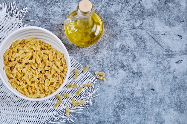 Foto gratuita un cuenco de pasta cruda con aceite de oliva en azul.