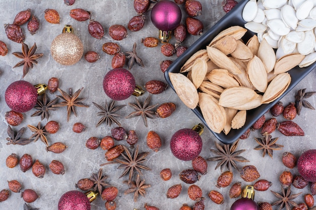 Cuenco de pistacho y semillas de calabaza con rosa mosqueta y bolas de Navidad.