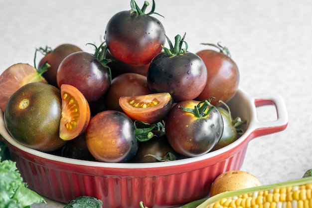 Un cuenco de primer plano con tomates negros maduros en la mesa de la cocina