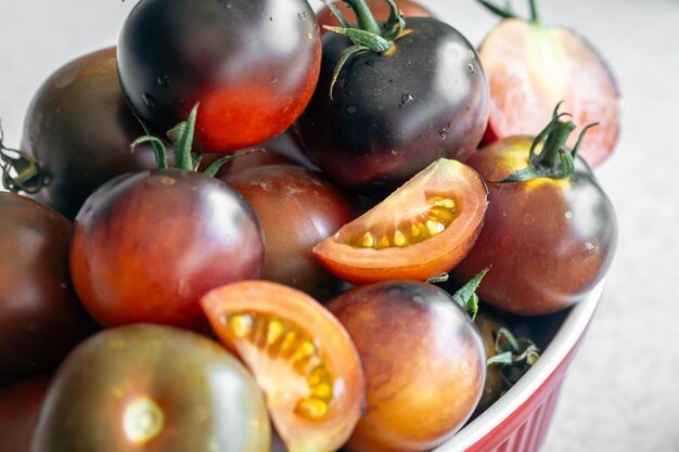 Un cuenco de primer plano con tomates negros maduros en la mesa de la cocina