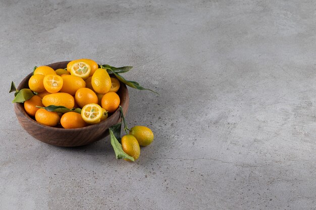 Cuenco profundo de kumquats jugosos frescos sobre la superficie de piedra