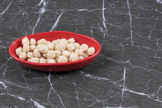 Cuenco rojo de bolas de cereales dulces para el desayuno. Ilustración de alta calidad