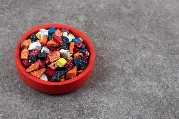 Cuenco rojo de caramelos de piedra de colores sobre la mesa de piedra.
