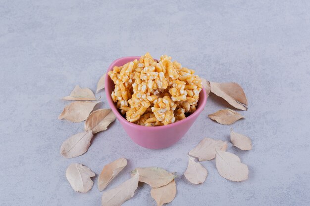 Cuenco rosa de caramelos duros con nueces en piedra.