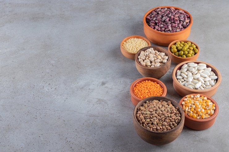 Foto gratuito cuencos de arcilla llenos de lentejas crudas, guisantes y frijoles sobre fondo de piedra.
