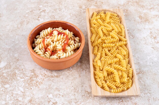 Cuencos de arcilla y madera de deliciosa pasta sobre una superficie de mármol