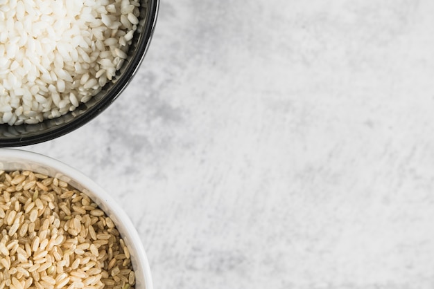 Cuencos con arroz blanco y marrón sobre mesa.