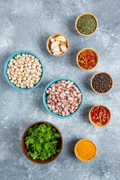 Cuencos azules de frijoles crudos y especias sobre fondo de mármol.