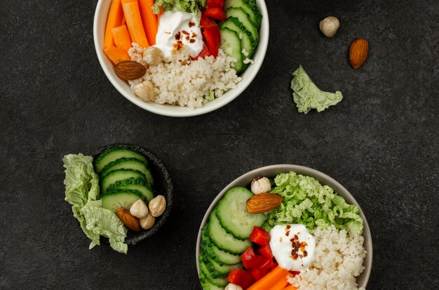 Cuencos de ensalada de verduras de vista superior con cuscús y pepinos