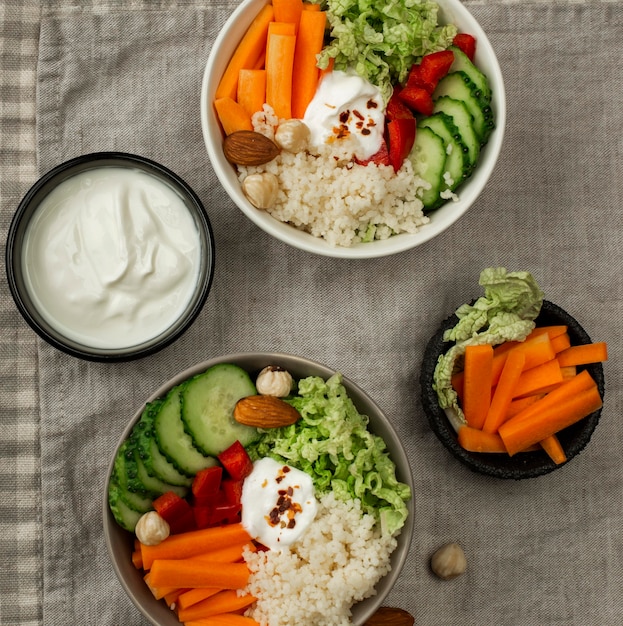 Cuencos de ensalada de verduras de vista superior con cuscús y yogur