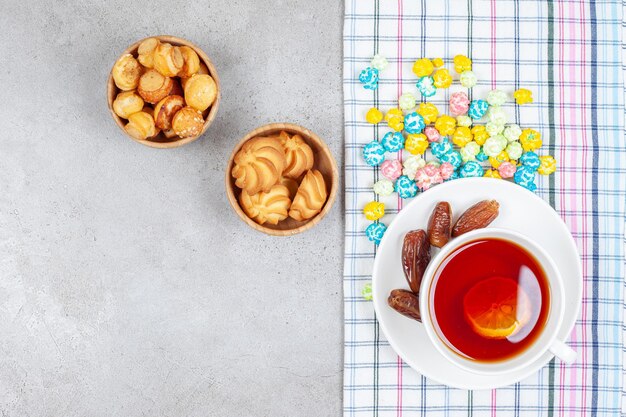 Cuencos de galletas y té con dátiles y caramelos sobre fondo de mármol. Foto de alta calidad