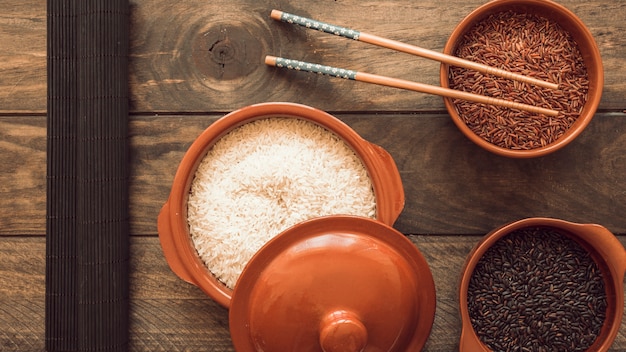 Foto gratuita cuencos de granos de arroz crudo con los palillos en la mesa de madera