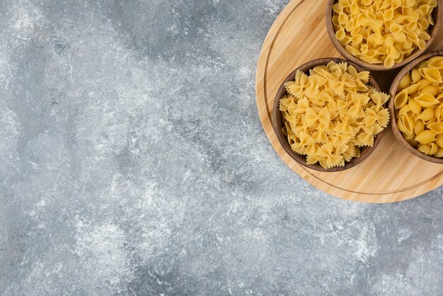 Cuencos de madera de pasta seca cruda sobre superficie de mármol.