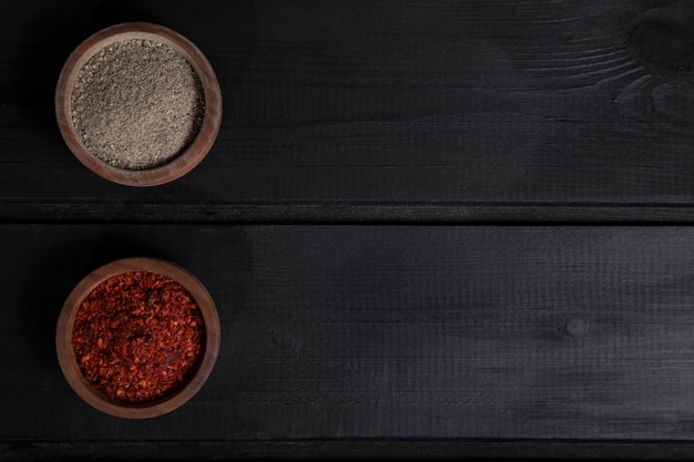 Foto gratuita cuencos de madera de pimienta roja y gris especiados colocados sobre la mesa de madera. foto de alta calidad