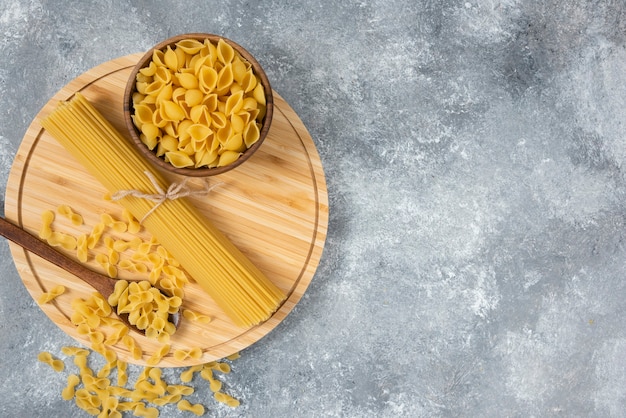 Cuencos de pasta seca cruda y espaguetis sobre superficie de mármol.