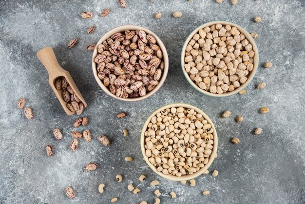 Cuencos de varios frijoles crudos sobre la superficie de la mesa de mármol.