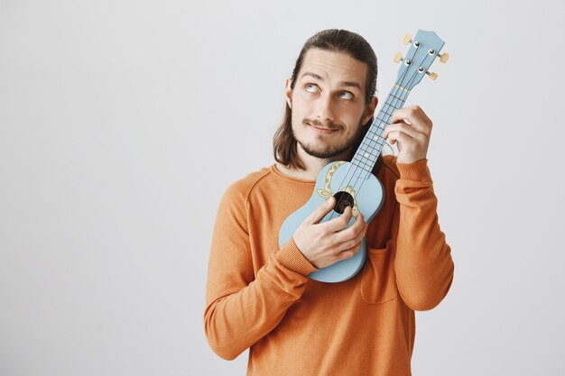 Cuerdas de melodía de chico lindo hipster, tocando el ukelele